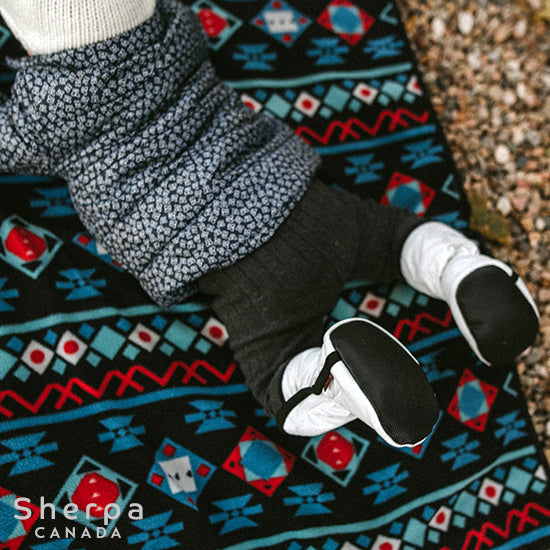 petite fille portant des bottines Moki de couleur noir jouant sur une couverture de polar à l'extérieur